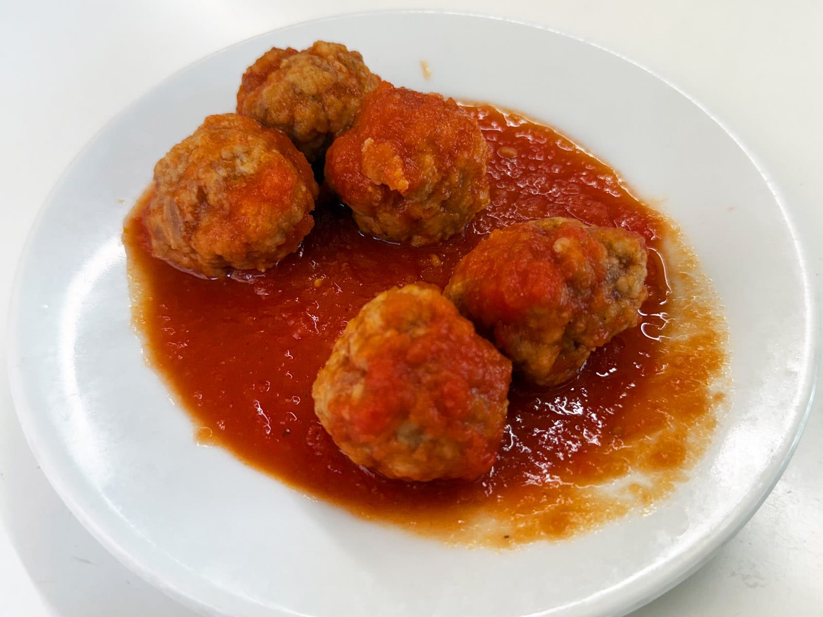 Plato de albóndigas caseras del Bar Tomás de Sarrià, cinco piezas napadas con salsa de tomate