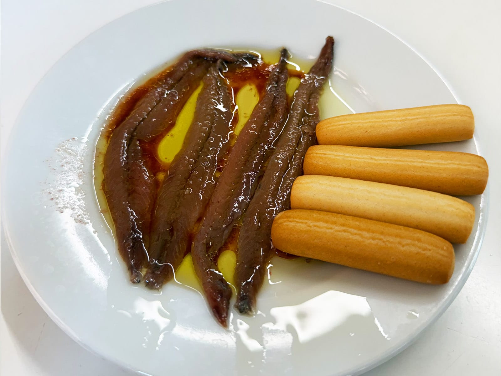 Las cuatro anchoas del Cantábrico del Bar Tomás de Sarrià en aceite de oliva, servidas con palitos de pan