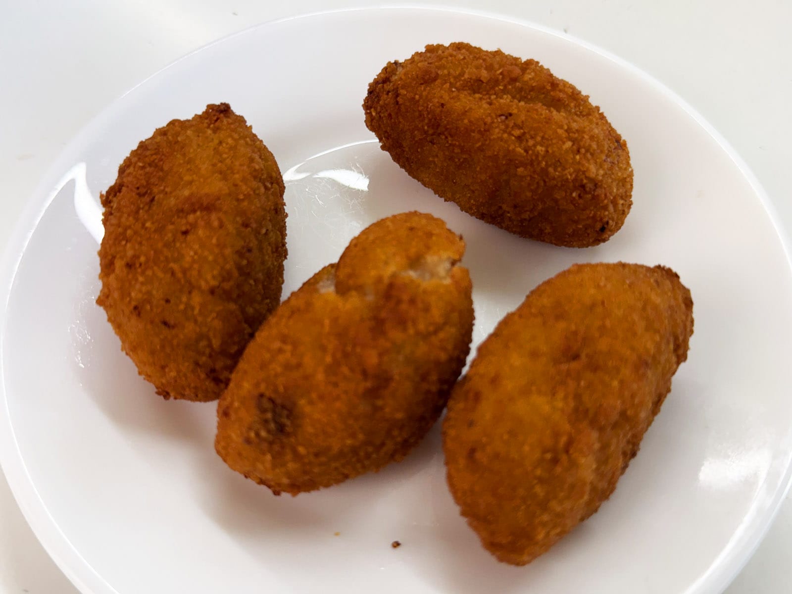Las cuatro croquetas del Bar Tomás de Sarrià en plato blanco, con el rebozado bien dorado y crujiente