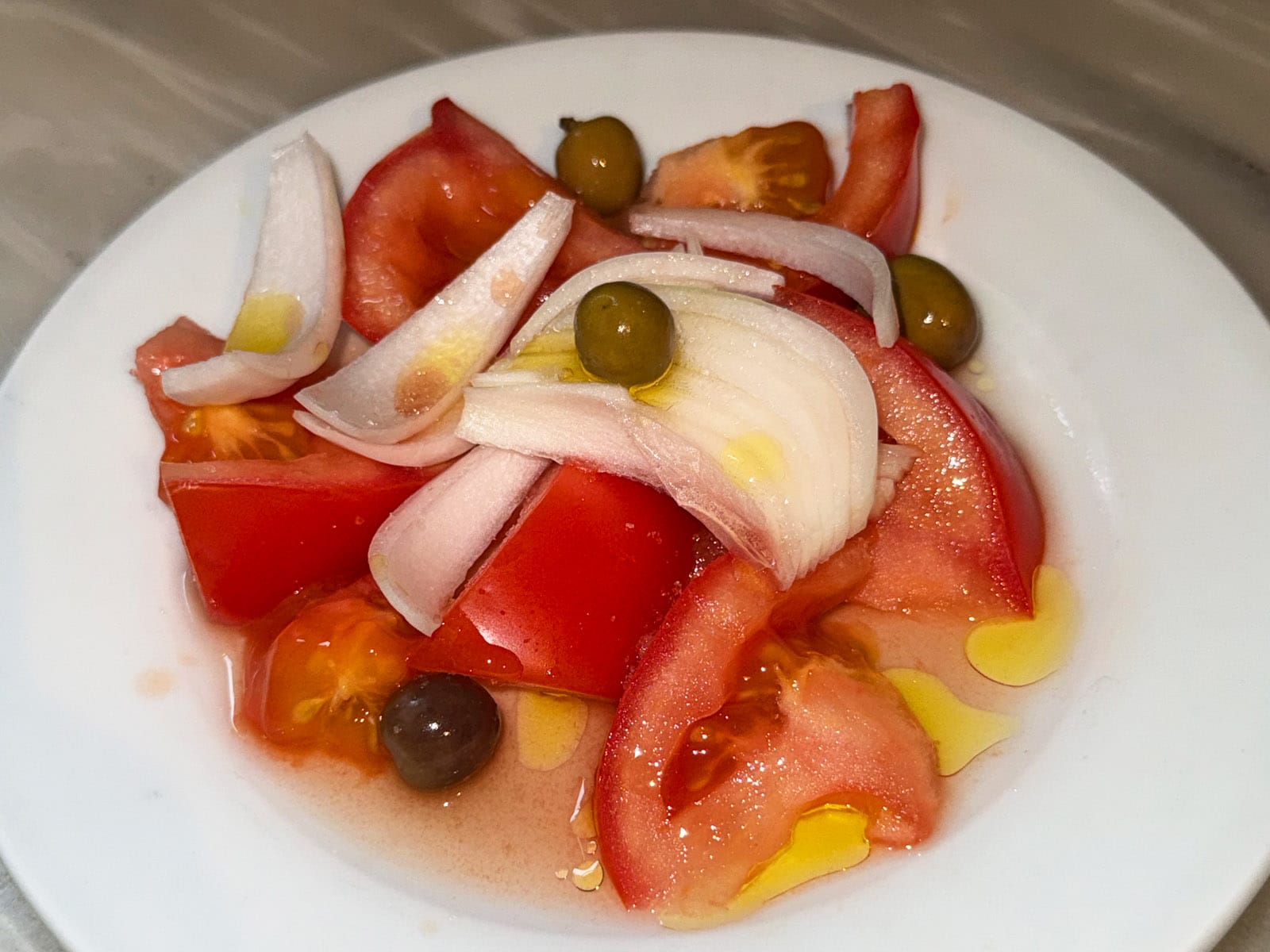 Ensalada de tomate del Bar La Plata: gajos de tomate maduro con cebolla en juliana, aceitunas y un chorro de aceite de oliva