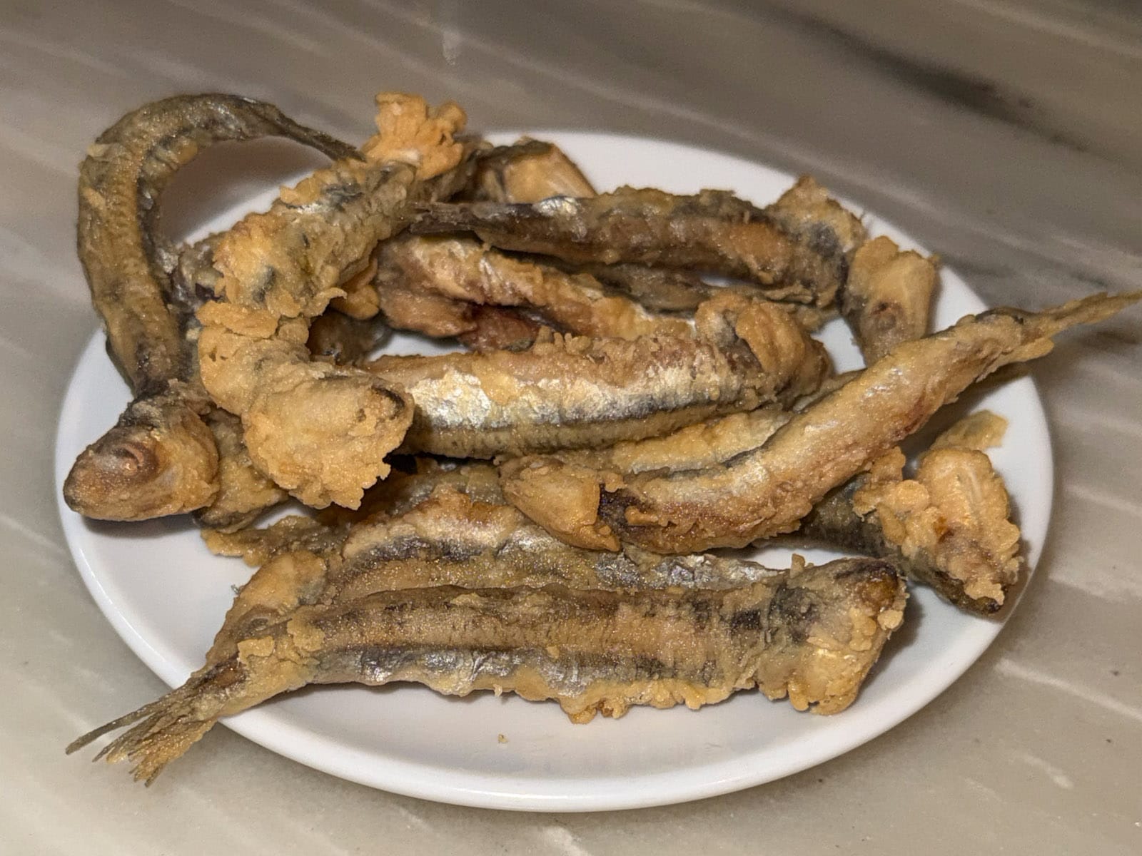 Platillo de pescadito frito del Bar La Plata: boquerones enteros rebozados y fritos, dorados y crujientes, servidos en plato blanco