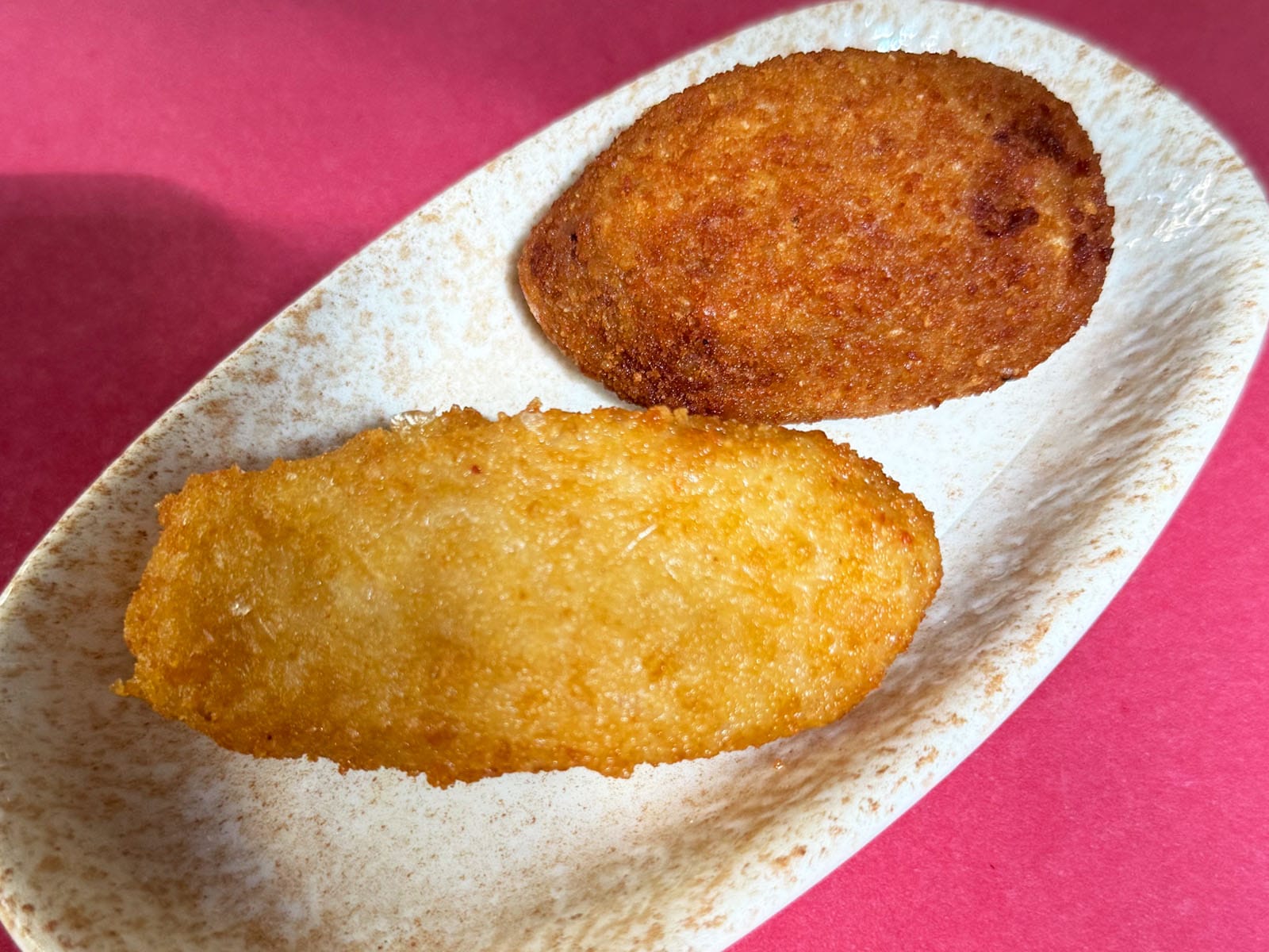 Dos croquetas del Canut en fuente ovalada de cerámica, con el rebozado dorado y crujiente