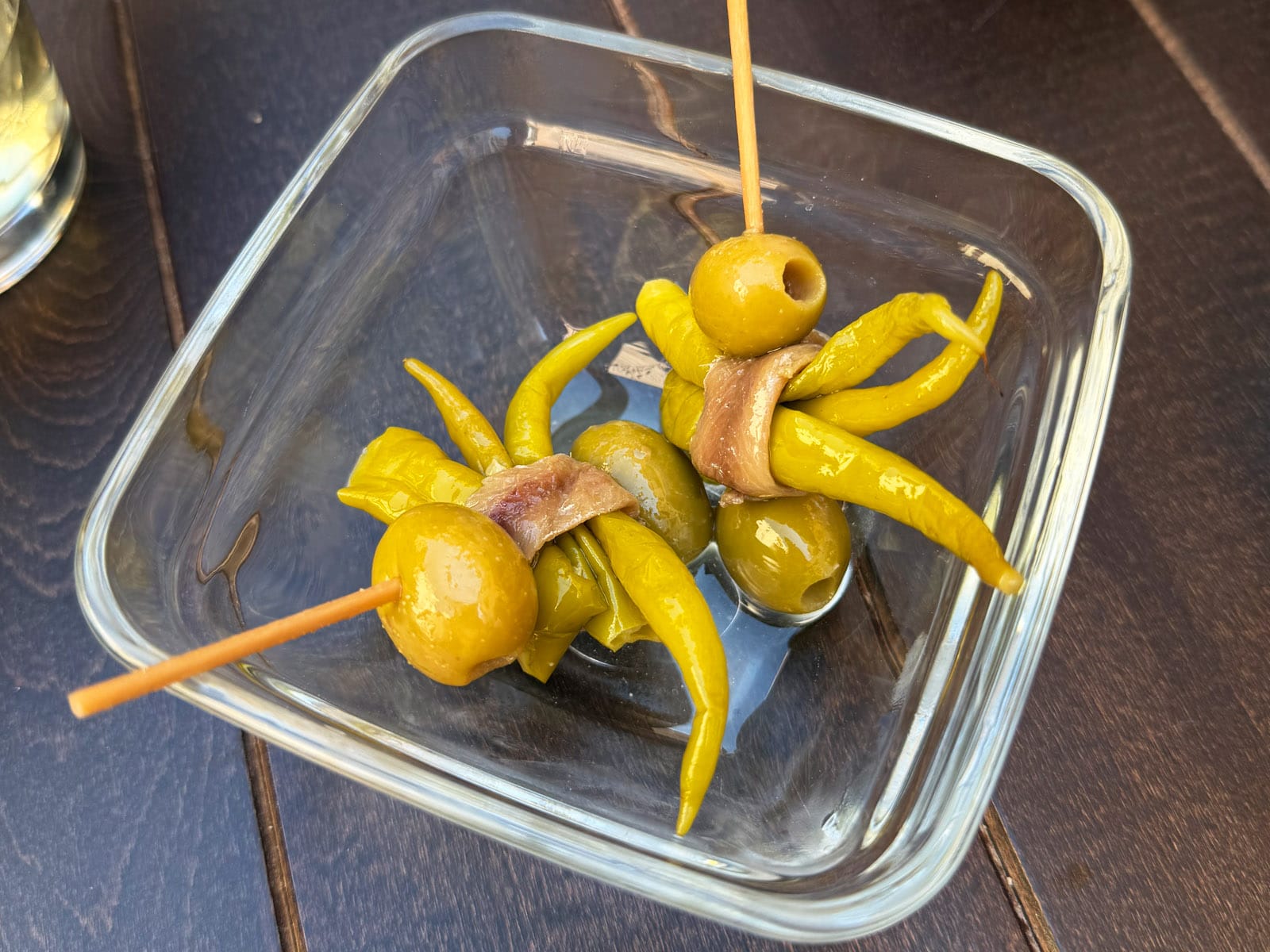 Dos gildas con aceitunas, piparras y anchoa en una fuente de cristal
