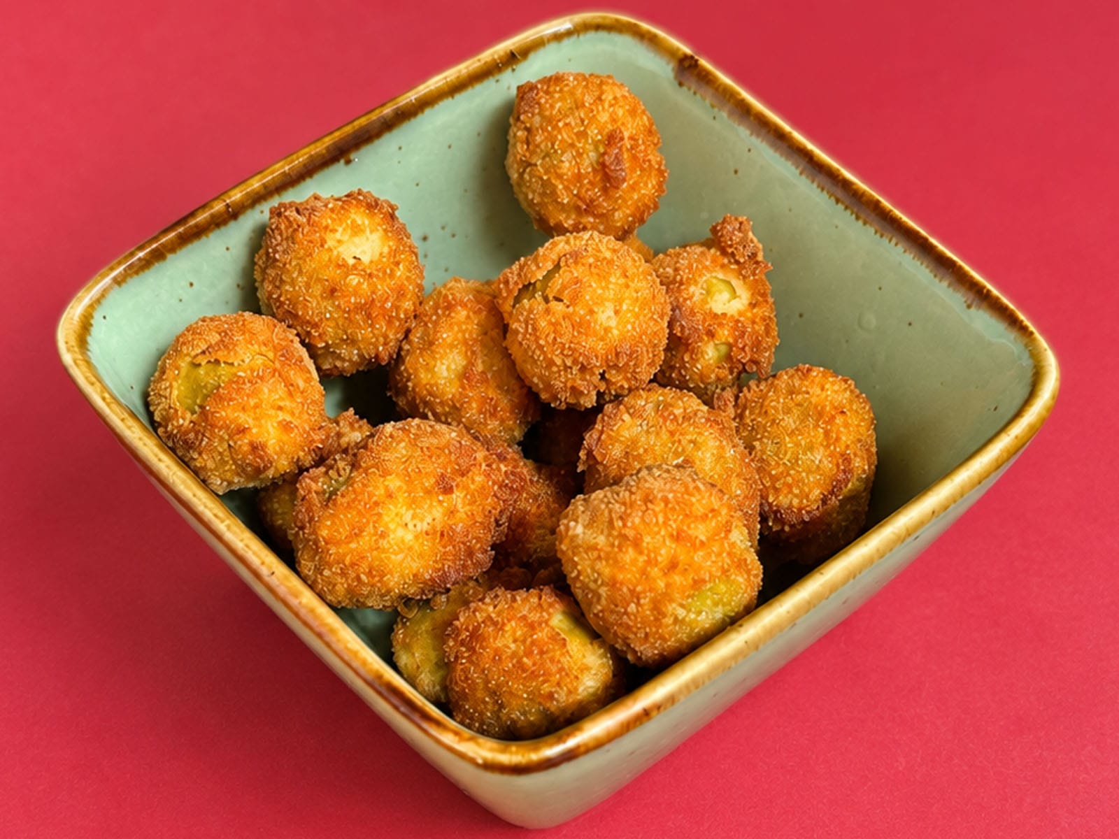 Cuenco de aceitunas crujientes del Canut: aceitunas rebozadas y fritas hasta quedar doradas por fuera, servidas en un bol de cerámica verde